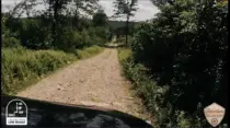 Berry Mountain climb picture 1. View over the hood of the FJ from the hero camera mounted to the windshield. Cruiser hood visible with a dusty-looking dirt and gravel path stretching out before it and green foliage on either side. Sticker on the bottom left of the image that says "Life is better in Low Range"