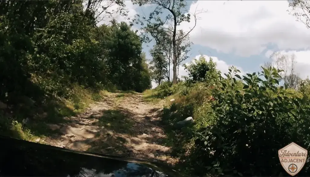 Berry Mountain climb picture 2. View over the hood of the FJ from the hero camera mounted to the hood. Cruiser Cruiser pointed up toward the sky emerging from the woods on a dirt two-track.