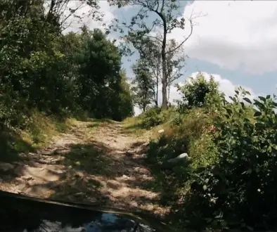 Berry Mountain climb picture 2. View over the hood of the FJ from the hero camera mounted to the hood. Cruiser Cruiser pointed up toward the sky emerging from the woods on a dirt two-track.