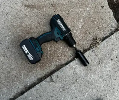 A Makita-brand drill is laying on the ground with a socket adapter and a 21mm deep impact socket is on the end. Representative of how important borrowed tools can be.