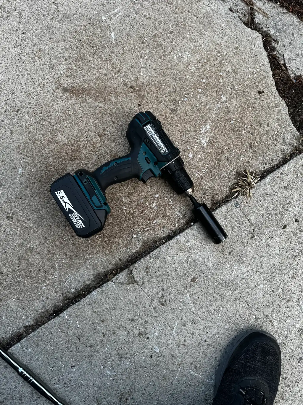 A Makita-brand drill is laying on the ground with a socket adapter and a 21mm deep impact socket is on the end. Representative of how important borrowed tools can be.