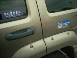 Two bumper stickers on the side of a gold Jeep. One is laid out like a Presidential political race bumper sticker, but instead of candidates it says, 